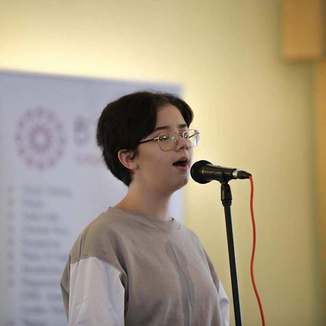 Young girl with glasses singing on microphone