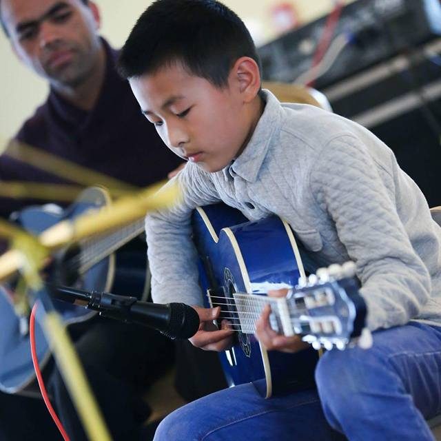 Young boy learning how to play the guitar